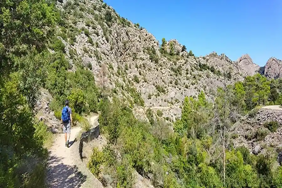 Tramo de la ruta al Toll Blau caminando al sol junto al río